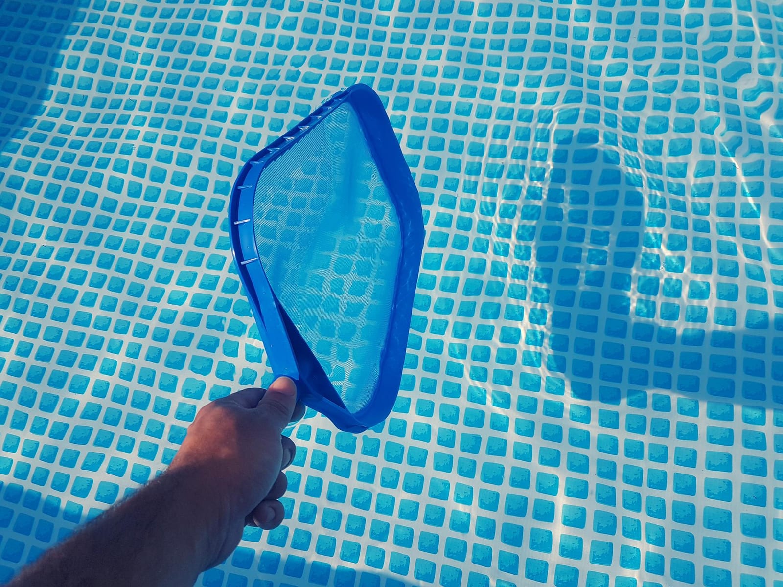 Installer laying ceramic tile during a pool shell build